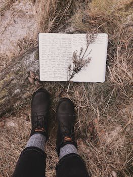 pexels-photo-2325297-2325297 Black boots on dried grass with an open journal in the fall season.